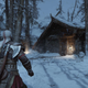 Kratos stands in the snow outside of his small log home.